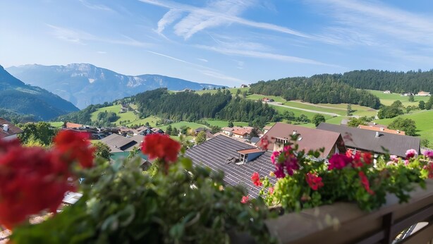 A view of a village with houses, mountains, and a clear sky.