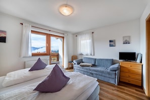 Une chambre avec deux lits, un canapé, une télévision et une fenêtre donnant sur un beau paysage.