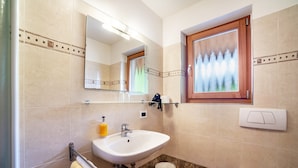 Une salle de bain équipée d’un lavabo, d’un miroir, d’une fenêtre et de toilettes.