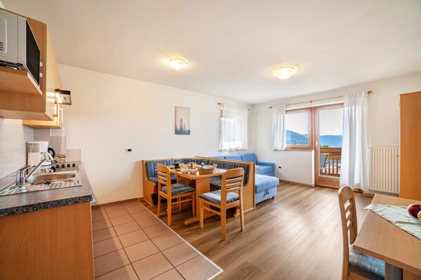A compact kitchen with a dining area, wooden furniture, and a view through a window.