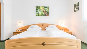 Una habitació amb un llit, dues taules de nit i dues làmpades penjades a la paret.
