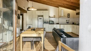 Una cocina moderna con armarios de madera, una mesa de comedor con sillas estampadas y un banco de cuero negro.