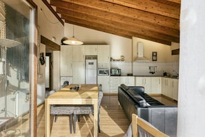 A modern kitchen with wooden cabinets, a dining table with patterned chairs, and a black leather bench.