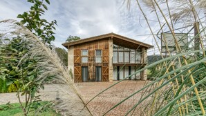 Un edificio de madera rústica con un sendero de ladrillo que conduce a él, rodeado de follaje.