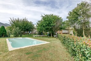 A swimming pool surrounded by grass and trees, with a building in the background.
