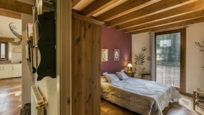 Un dormitorio con cama, vigas de madera en el techo, una ventana y vistas al exterior.