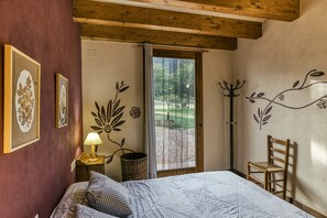 A bedroom with a bed, a chair, a lamp, a window, and wall art.