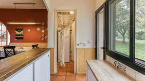Une cuisine dotée d’un plan de travail en bois, d’une fenêtre donnant sur les arbres et d’une porte menant à une autre pièce.