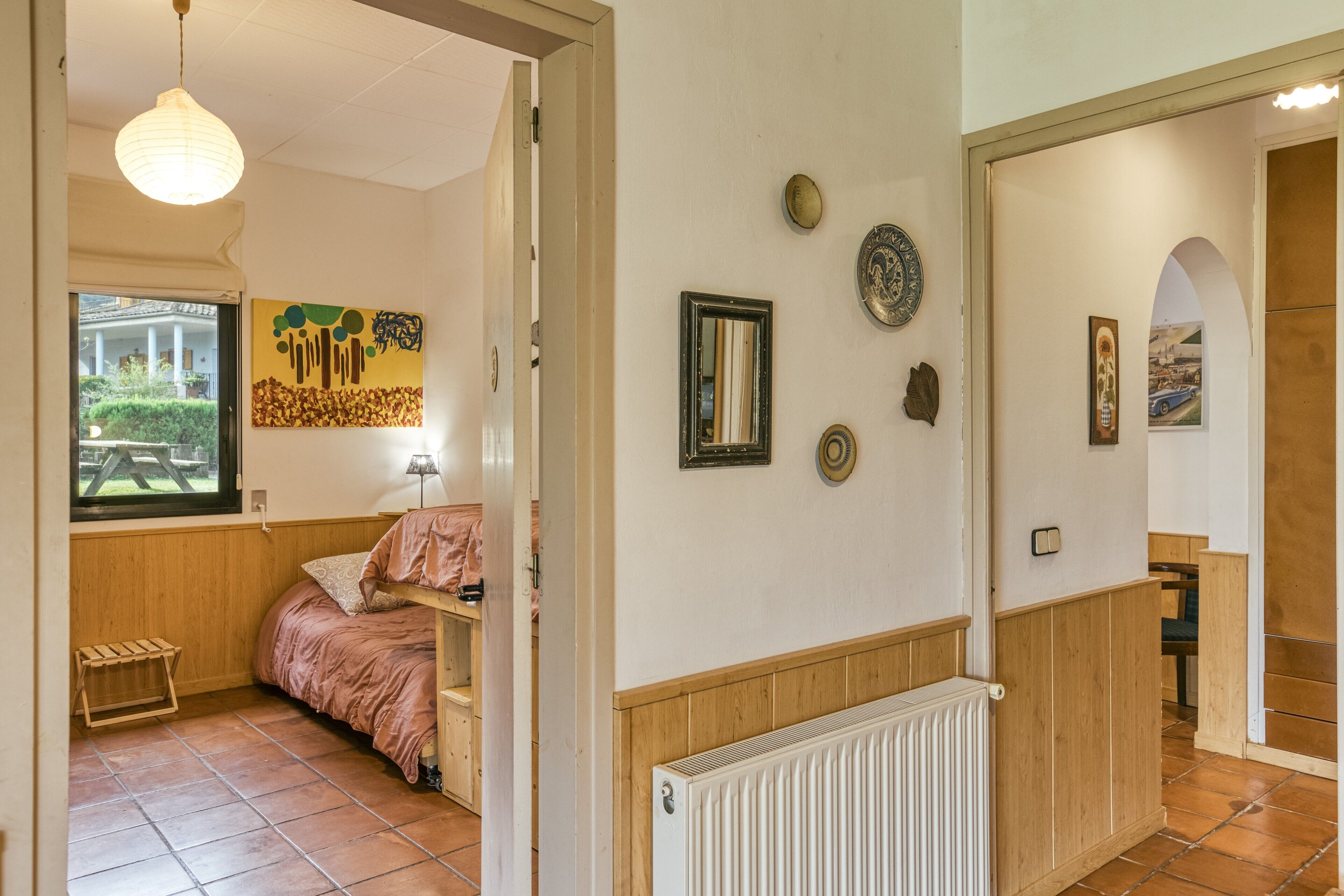A room with a bed, a window, a radiator, and wall decorations.