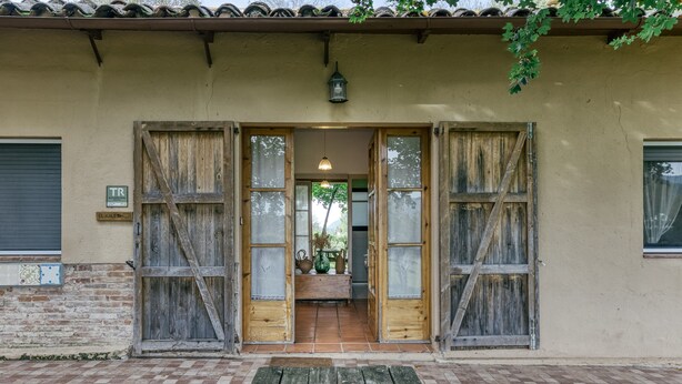 Une entrée d’immeuble avec des portes en bois, un patio carrelé et une lanterne suspendue.