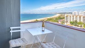 Un balcon avec une table, deux chaises, une bouteille de vin et des verres.