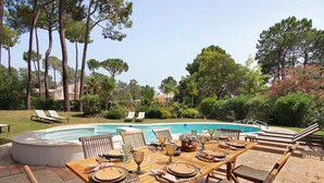 A poolside dining area with a table set for four, surrounded by lounge chairs and a swimming pool. - Holiday Home 'Casa Isabella' with Private Pool, Wi-Fi and Air Conditioning (Vilamoura)