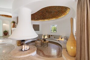Ein großzügiger Innenraum mit einer hohen weißen Säule, einer Ziegeldecke, einem runden Tisch und einer Couch.