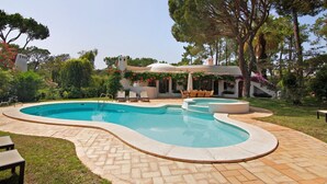 A swimming pool with a curved design, surrounded by a paved patio and outdoor furniture. - Holiday Home 'Casa Isabella' with Private Pool, Wi-Fi and Air Conditioning (Vilamoura)