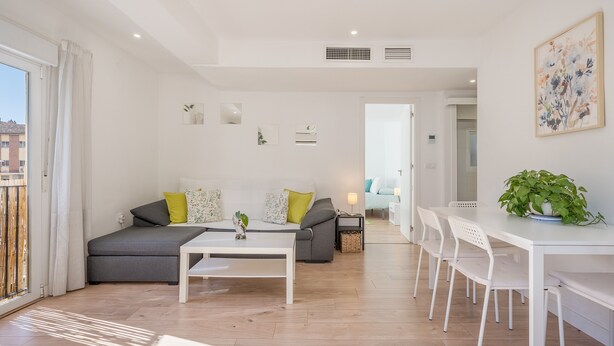 Uma sala de estar moderna com um sofá, mesa de centro e mesa de jantar.