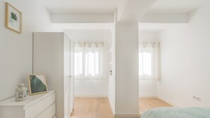 Quarto com cama, cômoda, guarda-roupa e janela com cortinas.