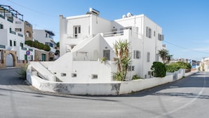 Um edifício branco com fachada curva, uma pequena palmeira e céu limpo.