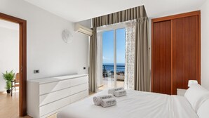 A hotel room with a bed, a desk, a chair, an air conditioning unit, and a view of the sea. - Holiday Apartment 'Obsidian Villa Bentayga' with Sea View and Wi-Fi (Adeje)