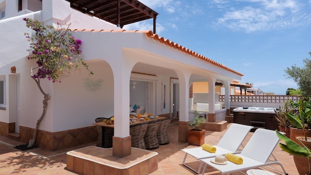 A patio with a barbecue, lounge chairs, and a dining area with outdoor furniture.