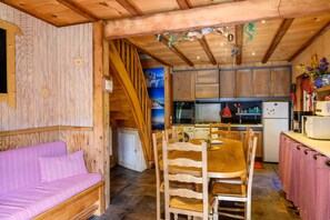 Un interior de madera con sofá, mesa de comedor, sillas, zona de cocina y lavadora.