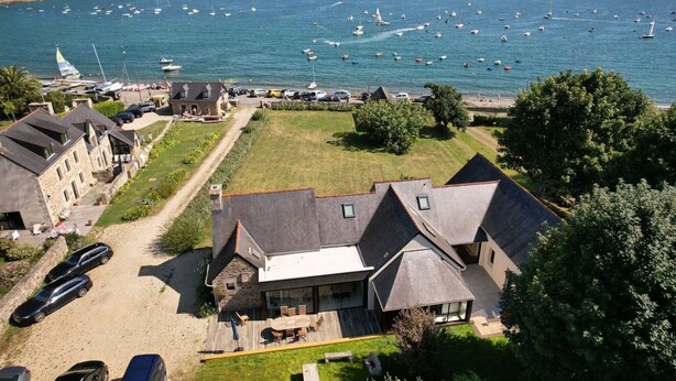 Ein Küsteneigentum mit einer großen Terrasse, Steinbauten und Blick auf das Meer mit Booten.