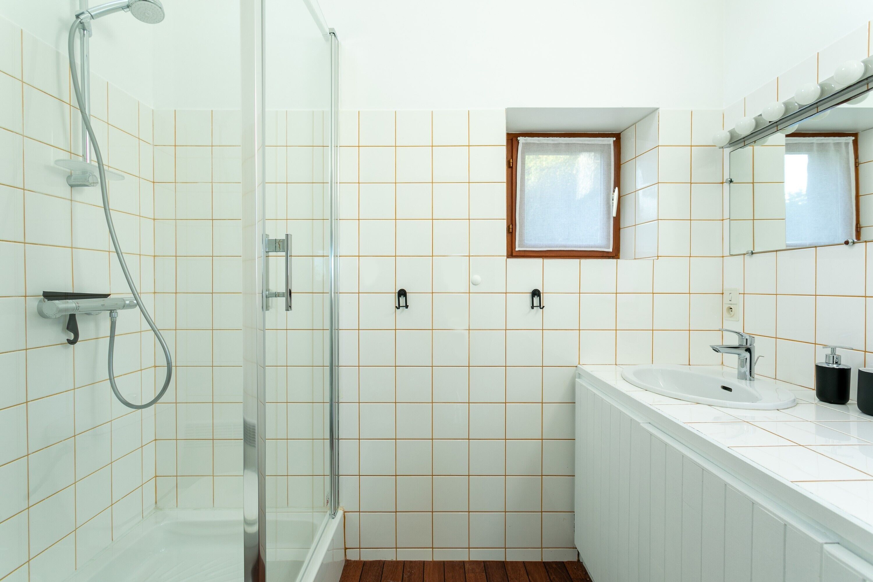 Une salle de bain avec une douche, un lavabo et une fenêtre.