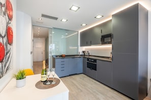 Une cuisine moderne avec des meubles gris, un four à micro-ondes et un coin repas avec une table dressée pour deux personnes.
