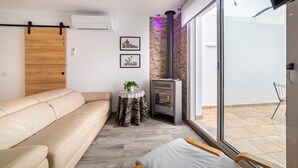 Un salon moderne avec un canapé, une petite table sur laquelle est posée une plante, une cheminée et une grande fenêtre.