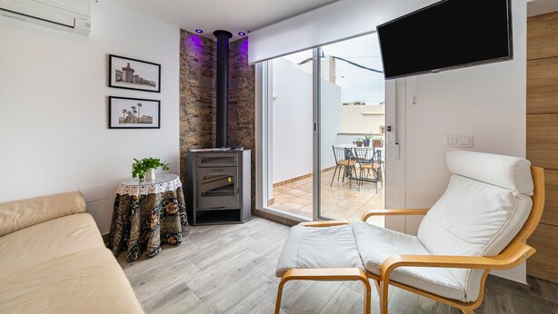 Un salon moderne comprenant un canapé, un fauteuil, une cheminée, un téléviseur et une vue sur l’extérieur.