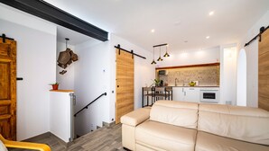 Un salon moderne avec un canapé, un escalier et un coin cuisine équipé d’un four à micro-ondes et de placards.