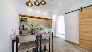 Une cuisine moderne avec une table et des chaises en bois, un four à micro-ondes et une porte coulissante.