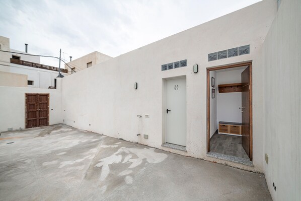 Un bâtiment blanc avec une porte, une porte en bois et une petite fenêtre.