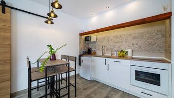 Eine moderne Küche mit Holztisch, weißen Schränken, einem eingebauten Backofen und Pendelleuchten.