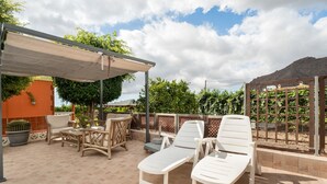 Ulkoterassi, jossa on aurinkotuoleja, pöytä ja pergola.