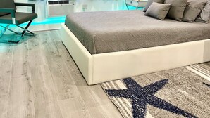 A modern bedroom with a large bed, a desk, and a ceiling fan. - Newly renovated apartment with ocean views, steps from the beach and Boardwalk! (Hollywood)