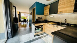 A modern kitchen with wooden cabinets, a black countertop, and a dining area with a table and chairs.