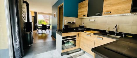 A modern kitchen with wooden cabinets, a black countertop, and a dining area with a table and chairs.
