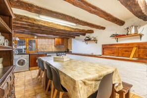 Una cocina rústica con vigas de madera, una mesa con sillas, una lavadora y una estufa.