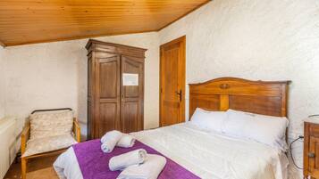 Une chambre à coucher avec un lit en bois, une chaise, une armoire et une petite table.