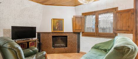A living room with a fireplace, leather armchairs, a television, and wooden cabinets.