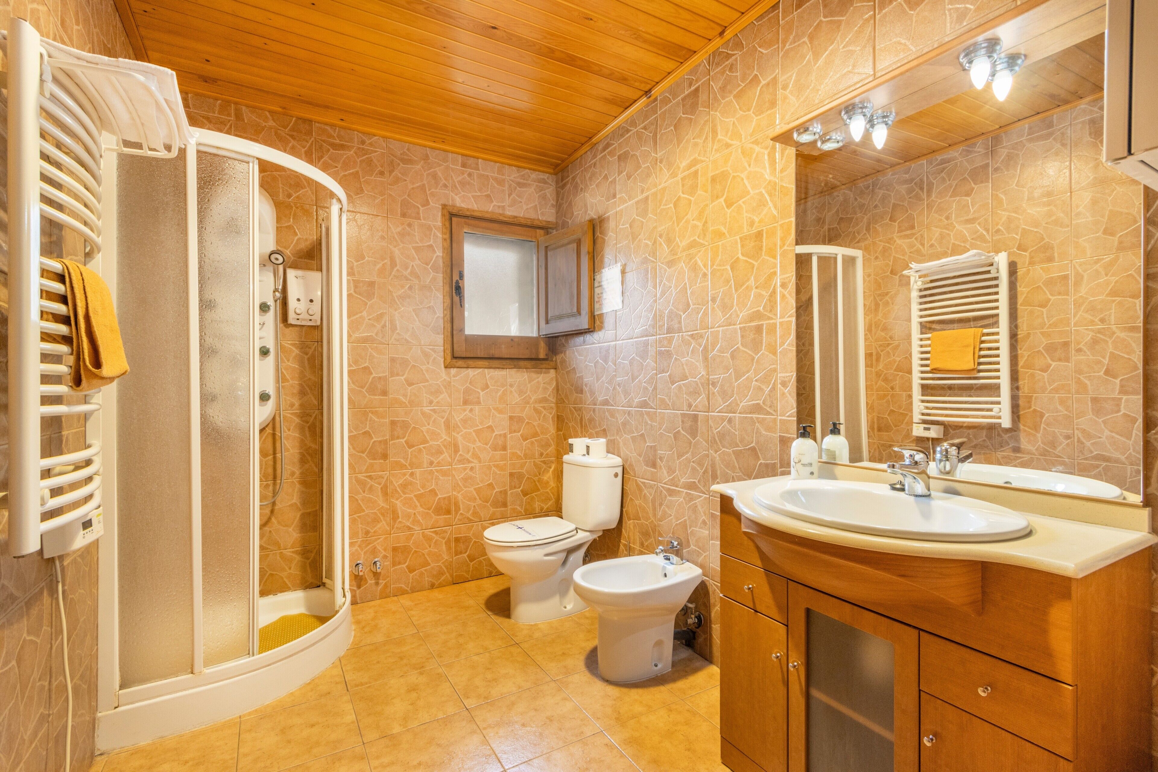 Une salle de bain équipée d’une douche, de toilettes, d’un bidet et d’un meuble-lavabo avec un miroir.