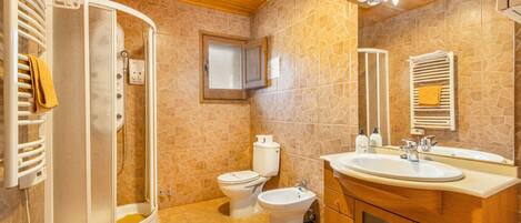 Une salle de bain équipée d’une douche, de toilettes, d’un bidet et d’un meuble-lavabo avec un miroir.