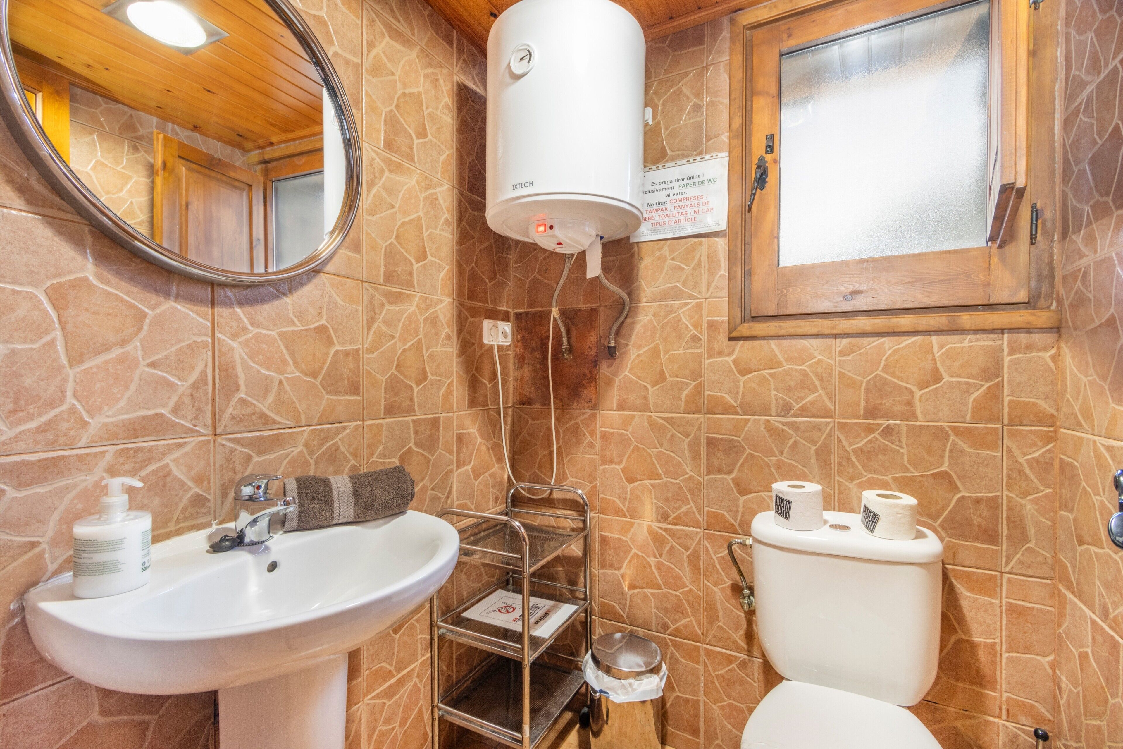 A bathroom with a white sink, a mirror, a toilet, and a water heater.