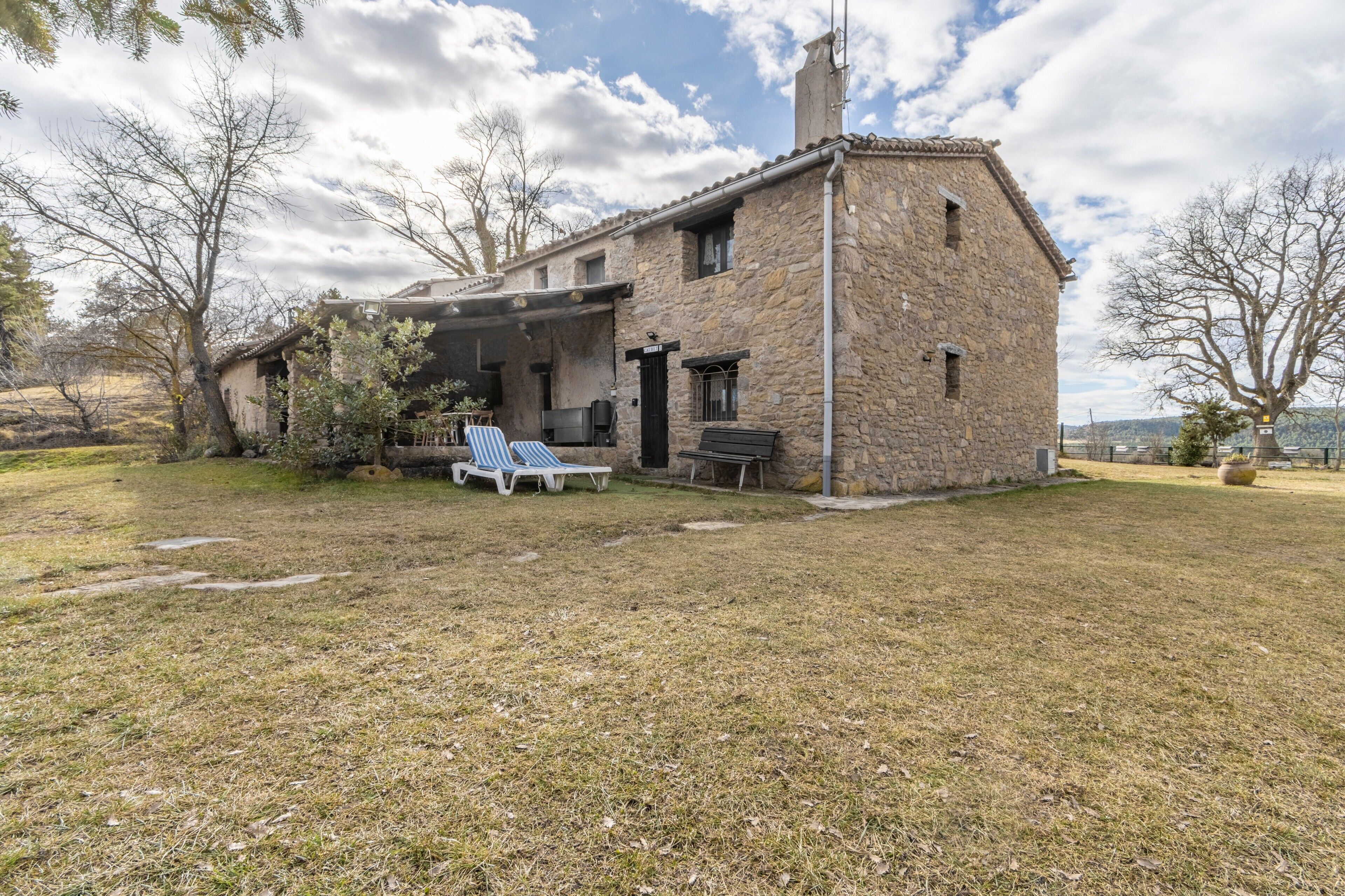 Una casa in pietra con un patio, due poltrone e un tavolino.