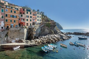A coastal town with colorful buildings, rocky cliffs, and boats anchored near the shore.