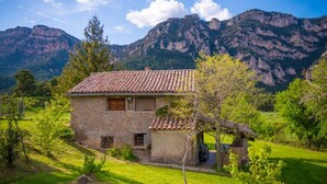 A stone house with a tiled roof, surrounded by lush greenery and mountains in the background. - Country House 'Can Caubet Lll' with Mountain View, Shared Pool and Wi-Fi (Capolat)