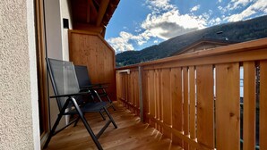 A wooden balcony with a view of a mountain range.