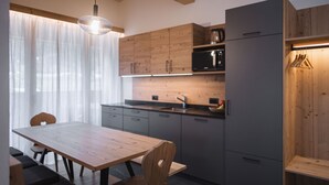 Una cocina moderna con armarios de madera, un microondas negro y un comedor con mesa y sillas de madera.
