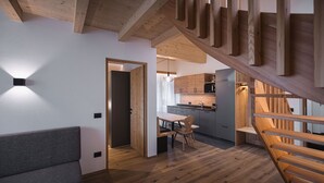 Un interior moderno con una escalera de madera, una zona de comedor y una cocina.