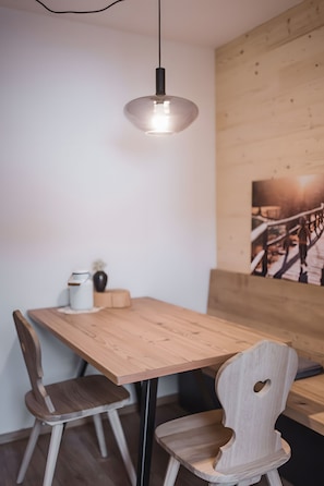 Un tavolo da pranzo in legno con due sedie, una lampada a sospensione e una parete in legno con un quadro.